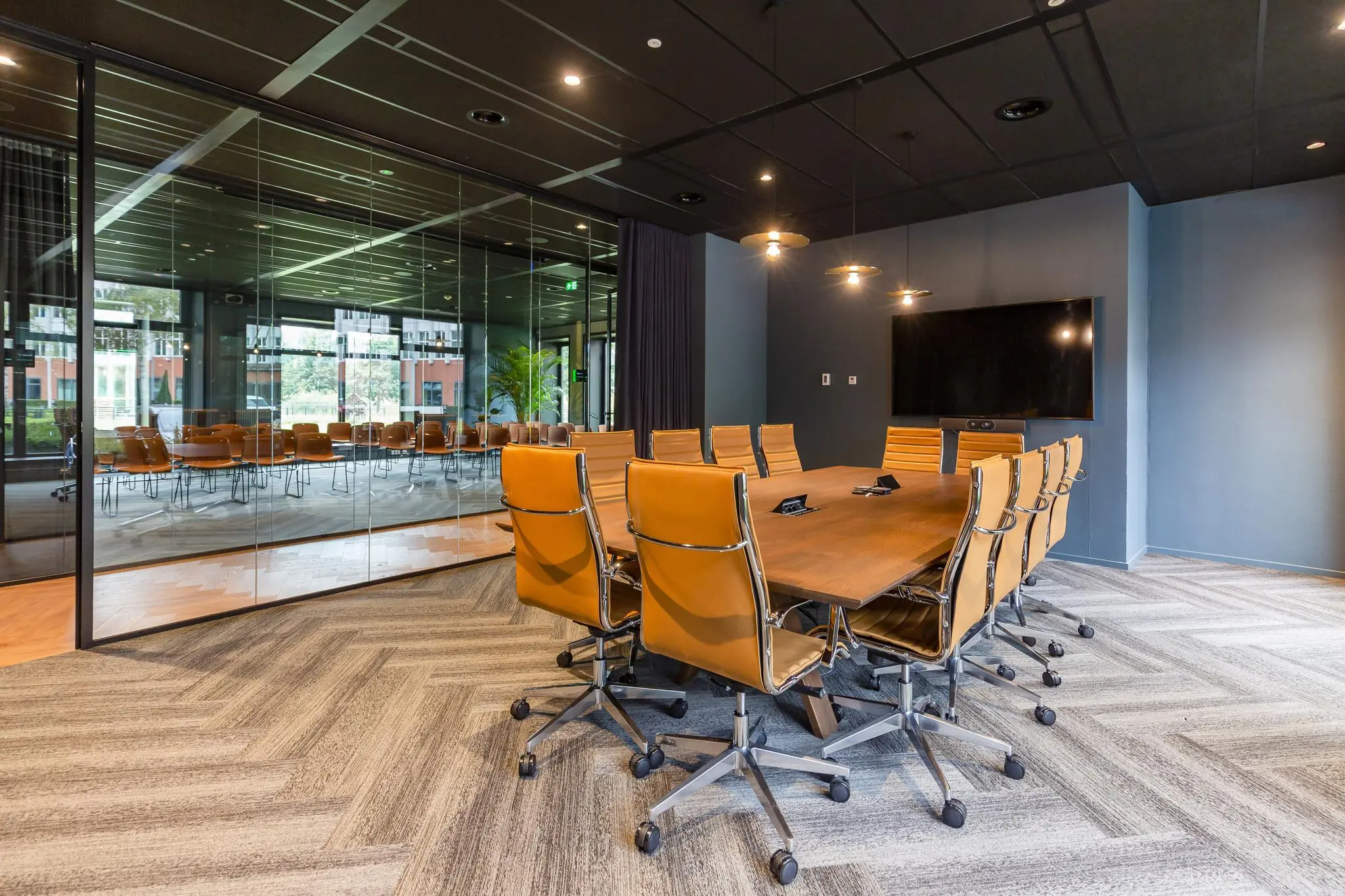 Moderne vergaderruimte met houten tafel, leren stoelen en een groot scherm aan de George Hintzenweg.